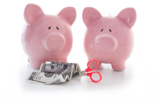 piggy banks with money and scissors for cutting costs