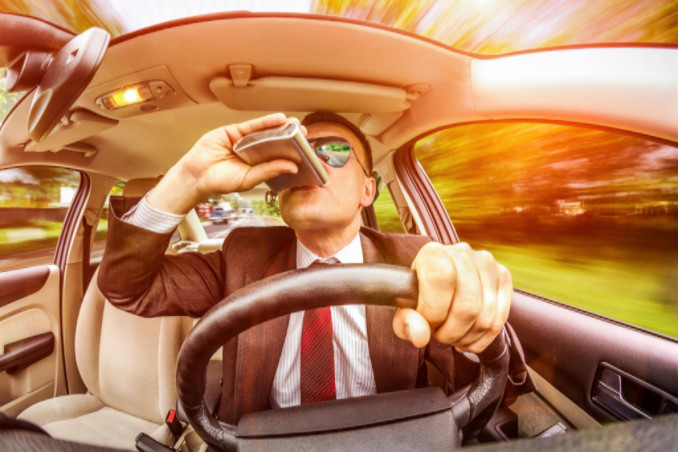 man in suit drinking behind the wheel: WorkingManLaw Personal Injury Article