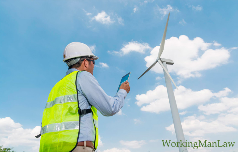 Safety inspector on the ground in front of a wind turbine